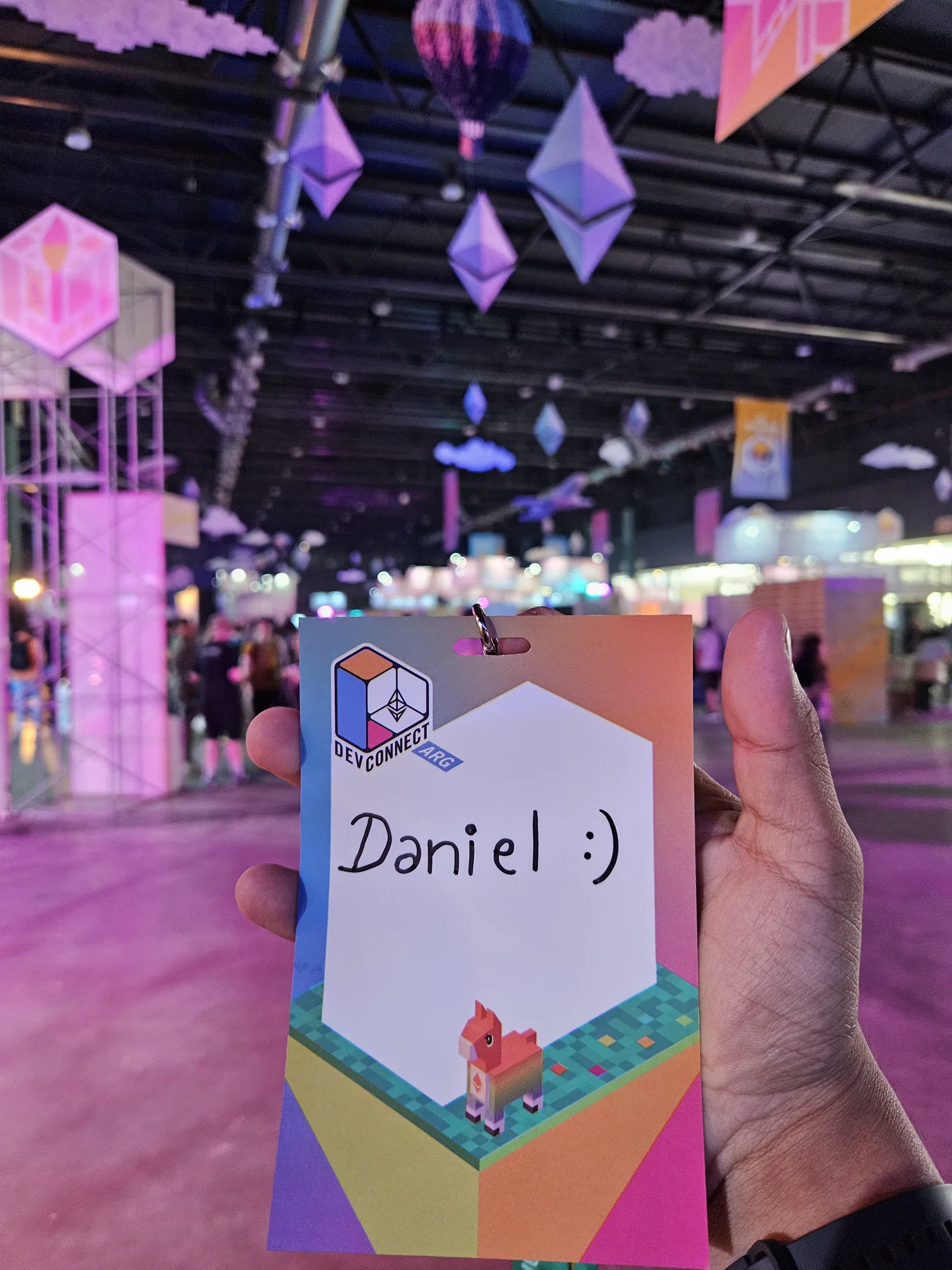 Credencial de voluntario de Devconnect sostenida en la mano.